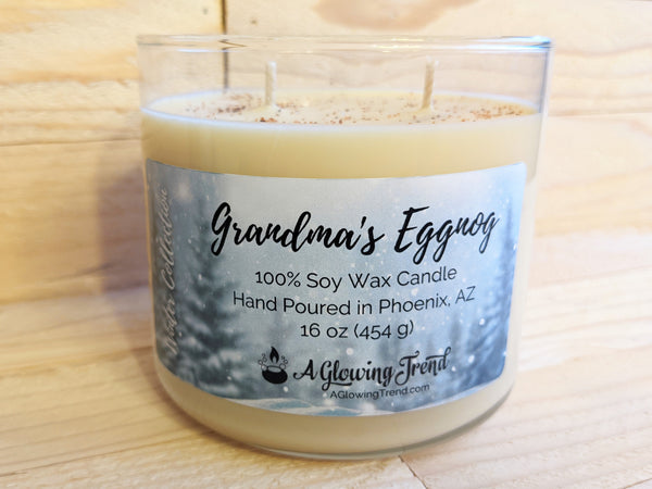 A 16 oz glass tumbler containing a light yellow Grandma's Eggnog scented soy candle topped with nutmeg by A Glowing Trend.
