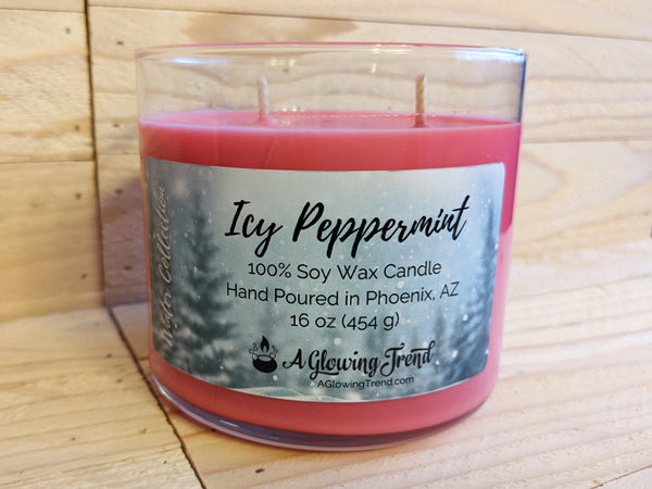 A 16 oz glass tumbler containing a red Icy Peppermint scented soy candle topped with glitter by A Glowing Trend.