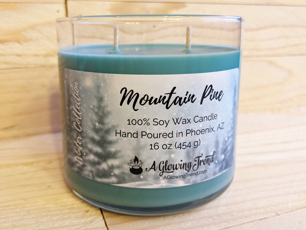 A 16 oz glass tumbler containing a green Mountain Pine scented soy candle by A Glowing Trend