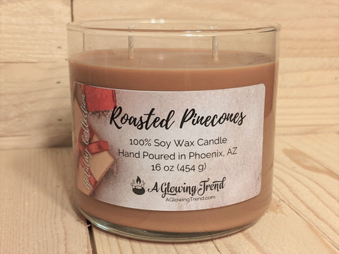 A 16 oz round glass tumbler containing a brown Roasted Pinecones scented soy candle by A Glowing Trend.