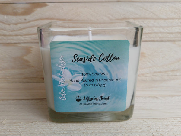 A 10 oz glass square containing a white Odor Neutralizing Seaside Cotton scented soy candle by A Glowing Trend.