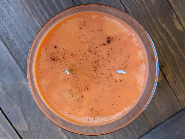 Close-up of orange Sweet Potato Spice scented soy candle by A Glowing Trend showing the real cinnamon dusted on top.
