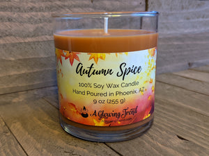 A 9 oz glass tumbler containing an orange-brown Autumn Spice scented soy candle by A Glowing Trend.