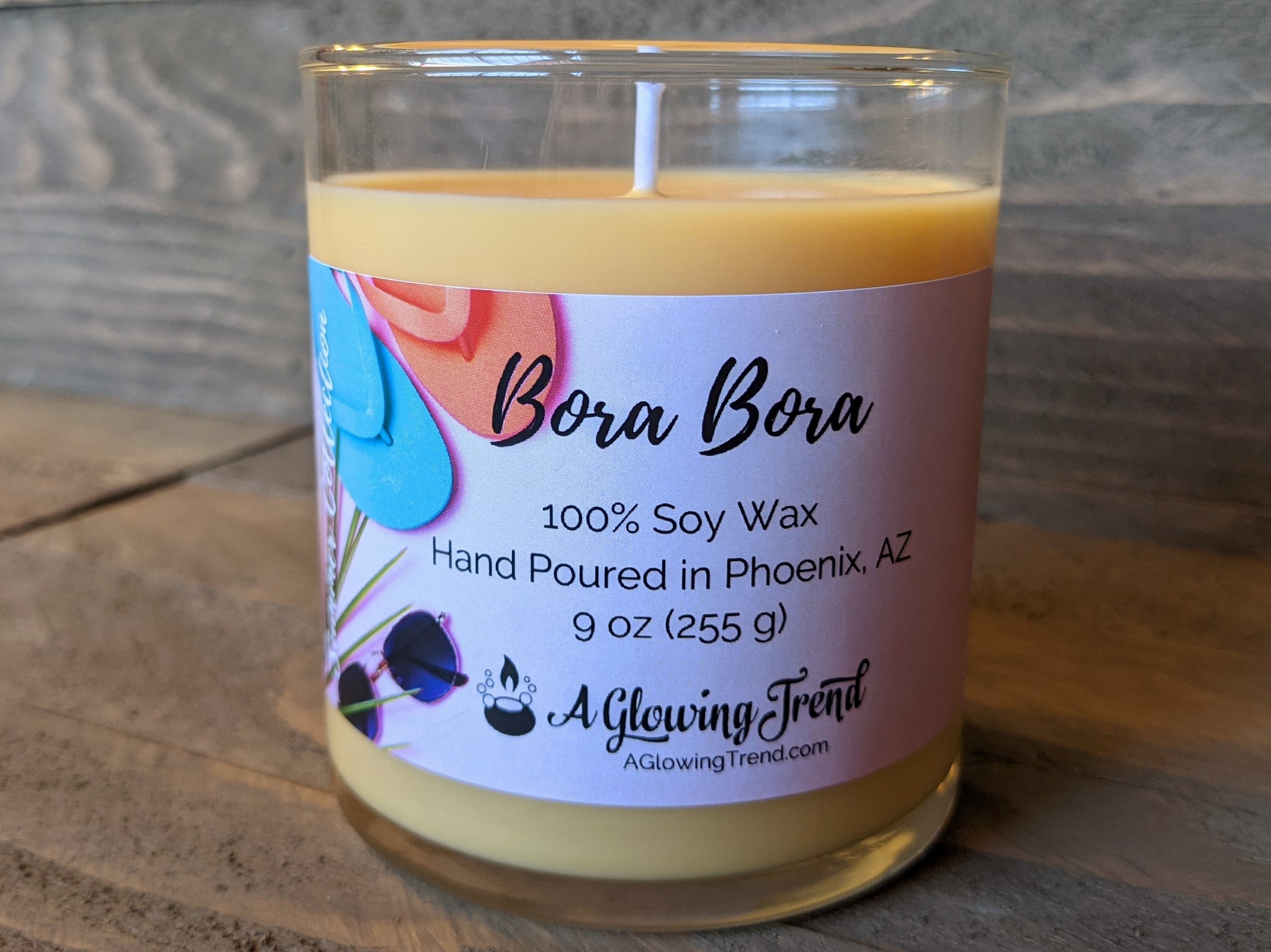 A 9 oz glass tumbler containing a light orange Bora Bora scented soy candle by A Glowing Trend.