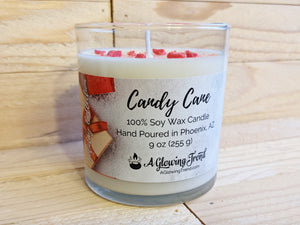 A 9 oz glass tumbler containing a white Candy Cane scented soy candle topped with bits of red wax by A Glowing Trend.