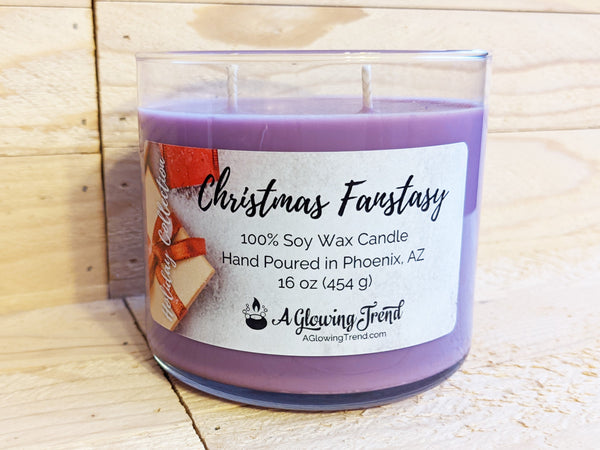 A 16 oz glass tumbler containing a purple Christmas Fantasy scented soy candle topped with glitter by A Glowing Trend.