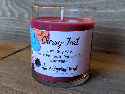 A 9 oz glass tumbler containing a dark red Cherry Tart scented soy candle by A Glowing Trend.