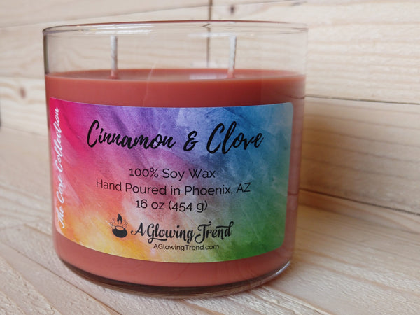 A 16 oz glass square containing a reddish-brown Cinnamon and Clove scented soy candle by A Glowing Trend