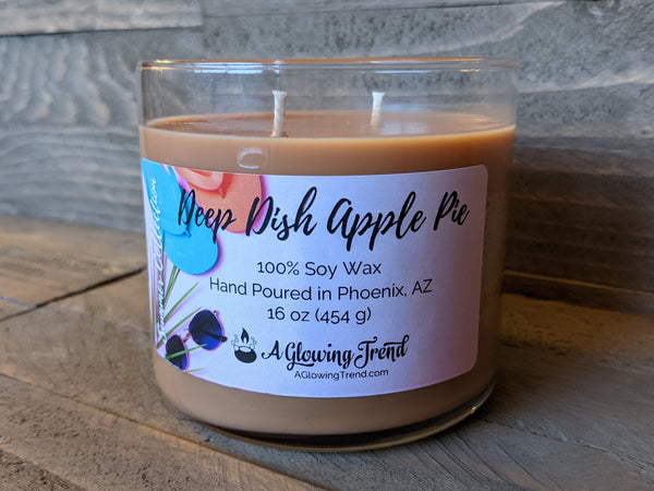 A 16 oz glass tumbler containing a golden brown Deep Dish Apple Pie scented soy candle by A Glowing Trend.