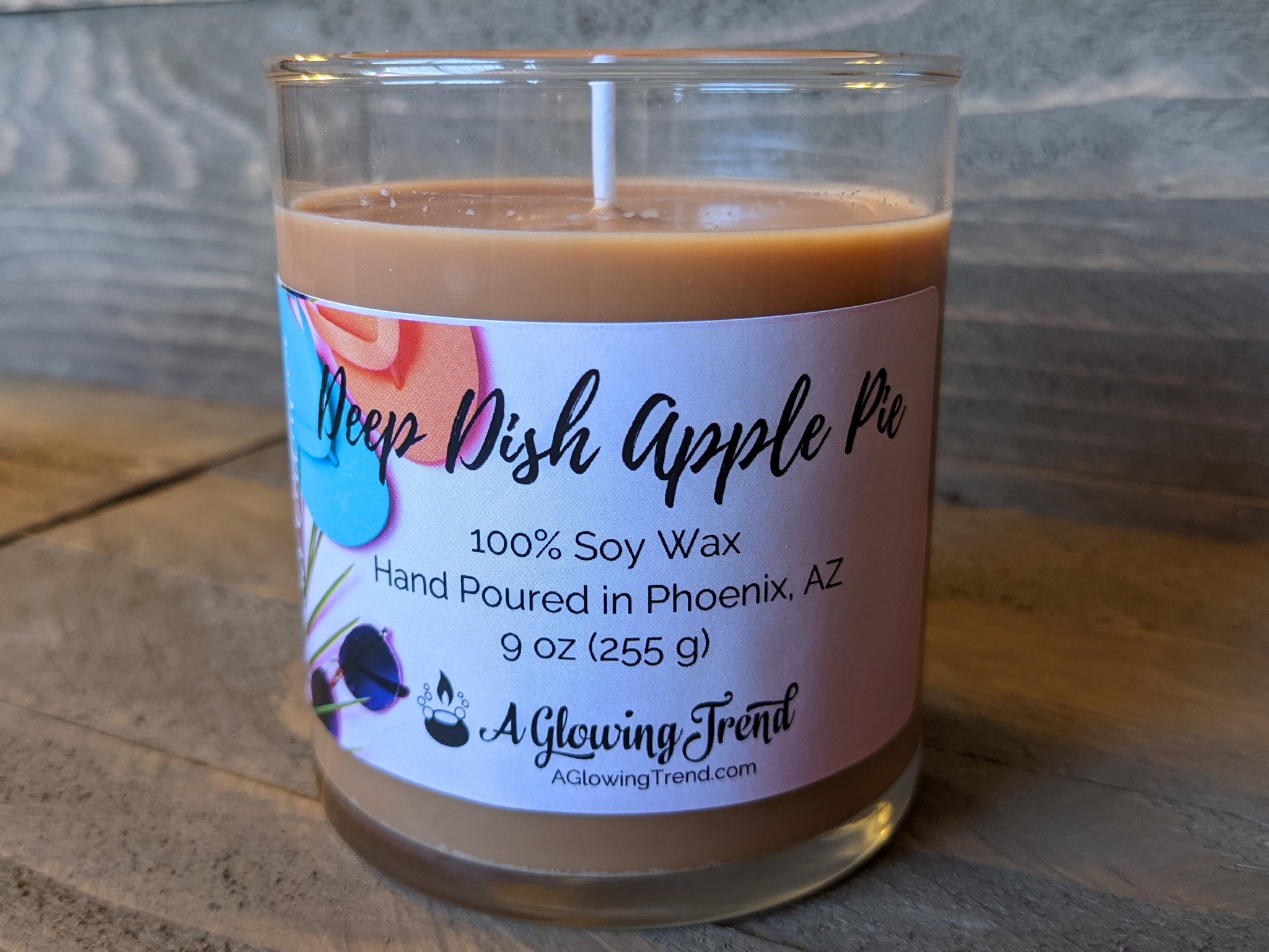 A 9 oz glass tumbler containing a golden brown Deep Dish Apple Pie scented soy candle by A Glowing Trend.