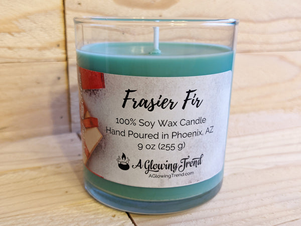 A 9 oz glass tumbler containing a green Frasier Fir scented soy candle by A Glowing Trend.