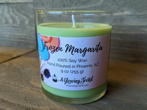 A 9 oz glass tumbler containing a light green Frozen Margarita scented soy candle by A Glowing Trend.