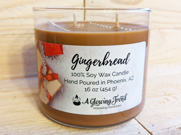 A 16 oz glass tumbler containing a brown Gingerbread scented soy candle topped with white wax drops by A Glowing Trend.