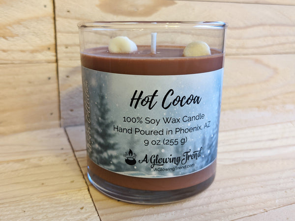 A 9 oz glass tumbler containing a brown Hot Cocoa scented soy candle topped with wax marshmallows by A Glowing Trend.
