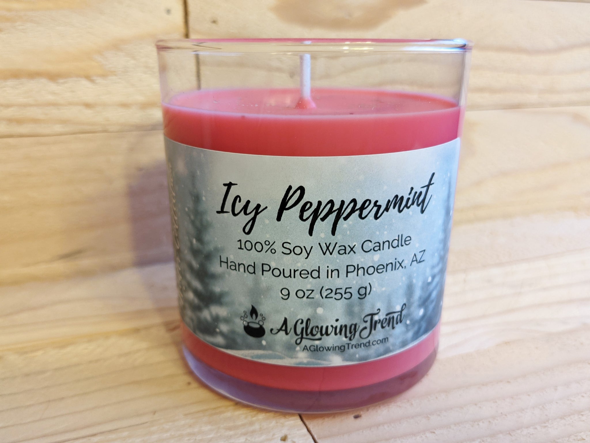 A 9 oz glass tumbler containing a red Icy Peppermint scented soy candle topped with glitter by A Glowing Trend.