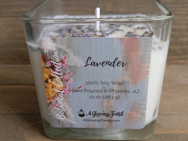 A 10 oz glass square containing a white Lavender scented soy candle topped with dried lavender buds by A Glowing Trend.