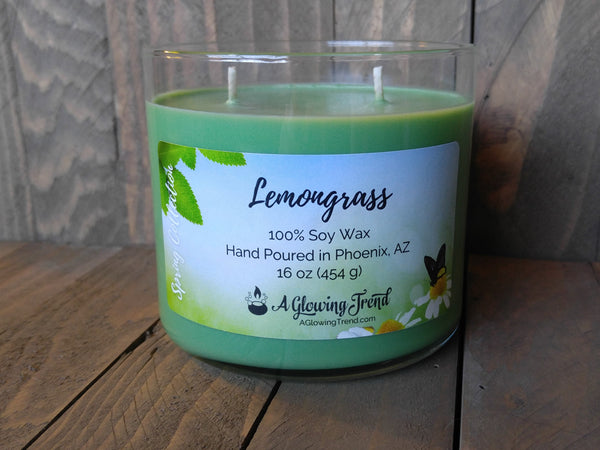 A 16 oz glass tumbler containing a yellow-green Lemongrass scented soy candle by A Glowing Trend.