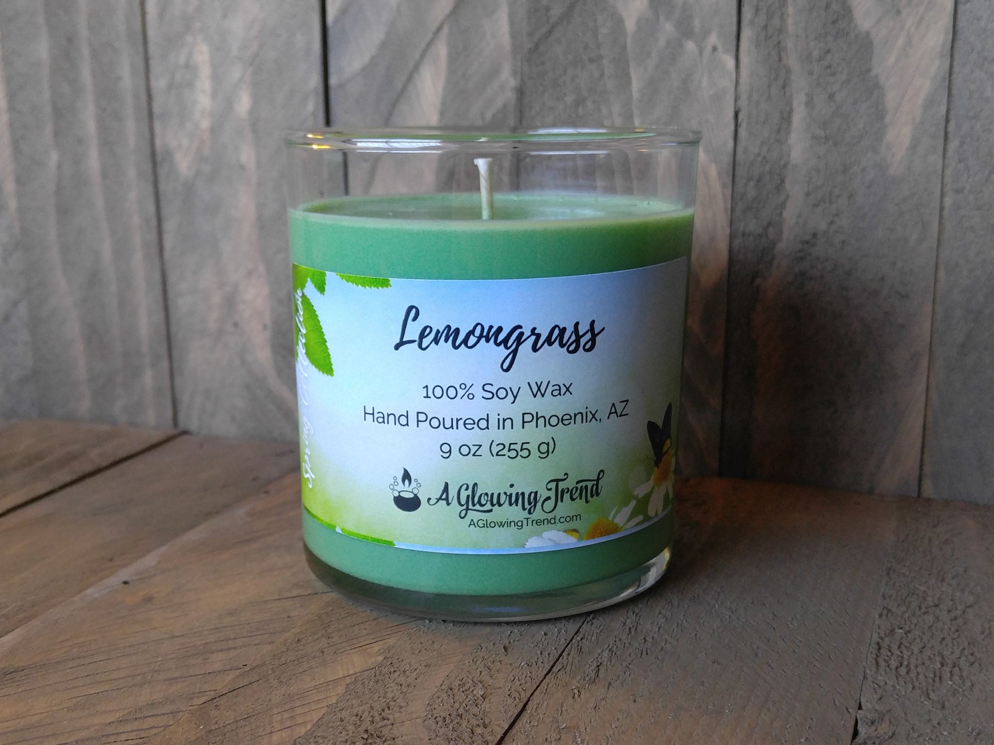 A 9 oz glass tumbler containing a yellow-green Lemongrass scented soy candle by A Glowing Trend.