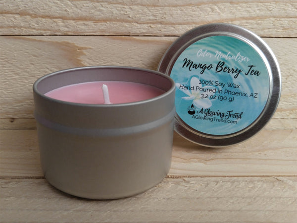 A 3.2 oz round tin containing a light pink Odor Neutralizing Mango Berry Tea scented soy candle by A Glowing Trend.