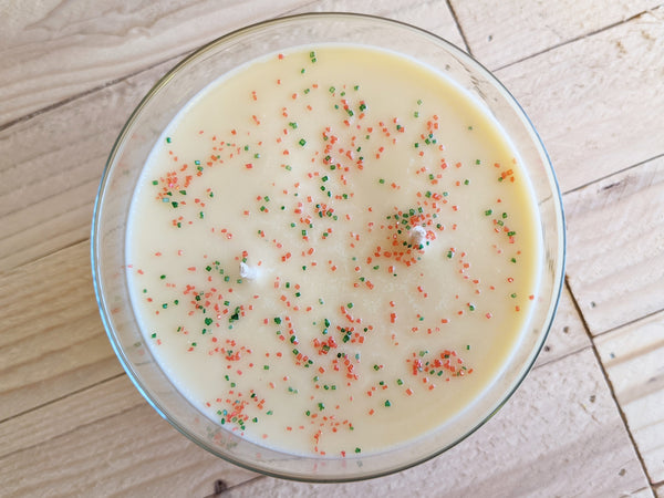 Close-up of yellow Sugar Cookie scented soy candle by A Glowing Trend showing with red and green sugar sprinkles.