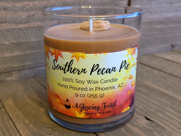 A 9 oz glass tumbler containing a brown Southern Pecan Pie scented soy candle topped with a wax pecan by A Glowing Trend.