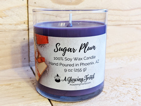 A 9 oz glass tumbler containing a purple Sugar Plum scented soy candle topped with glitter by A Glowing Trend.