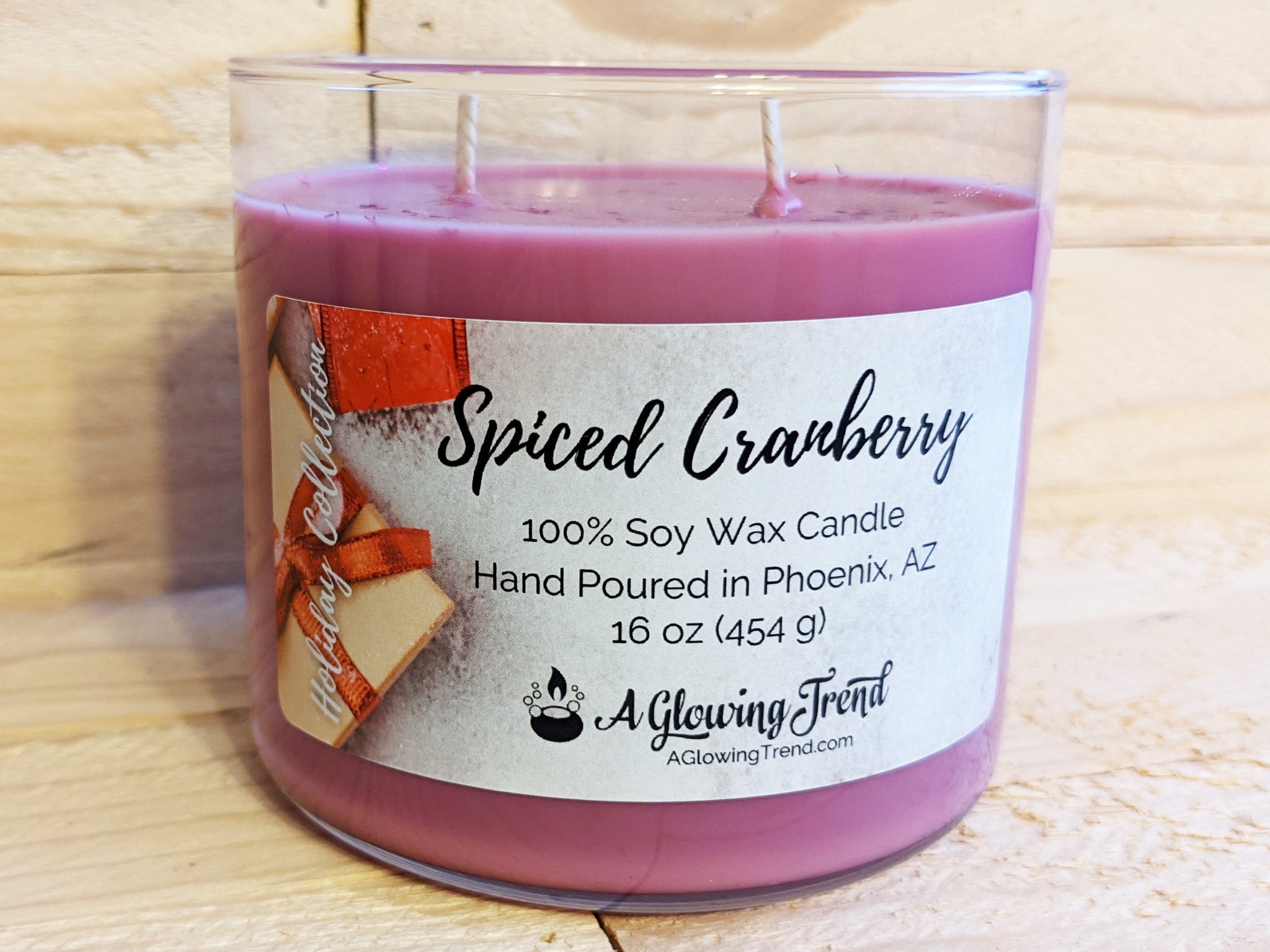 A 16 oz glass tumbler containing a purple Spiced Cranberry scented soy candle topped with glitter by A Glowing Trend.