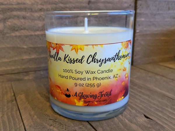 A 9 oz glass tumbler containing a white Vanilla Kissed Chrysanthemum scented soy candle by A Glowing Trend.