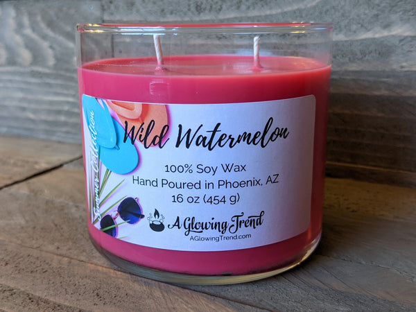 A 16 oz glass tumbler containing a red Wild Watermelon scented soy candle by A Glowing Trend.