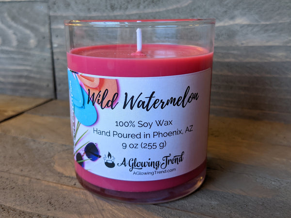 A 9 oz glass tumbler containing a red Wild Watermelon scented soy candle by A Glowing Trend.